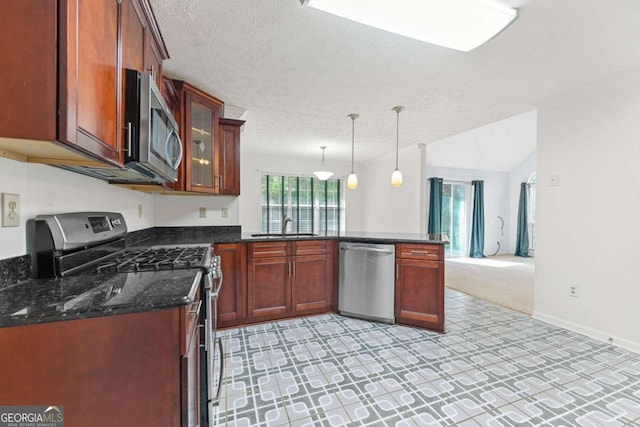 kitchen featuring pendant lighting, light colored carpet, dark stone countertops, appliances with stainless steel finishes, and a textured ceiling