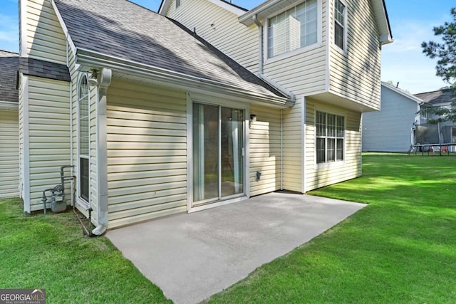 rear view of house with a yard, a trampoline, and a patio area