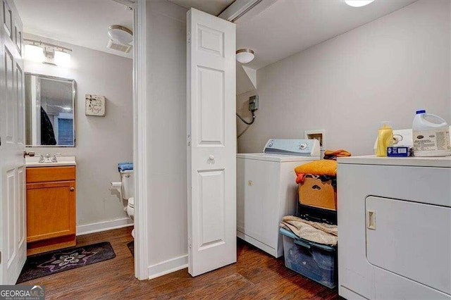 clothes washing area with washing machine and dryer, dark hardwood / wood-style flooring, and sink