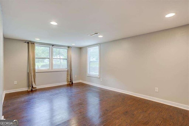 empty room with dark wood-type flooring, visible vents, a healthy amount of sunlight, and recessed lighting