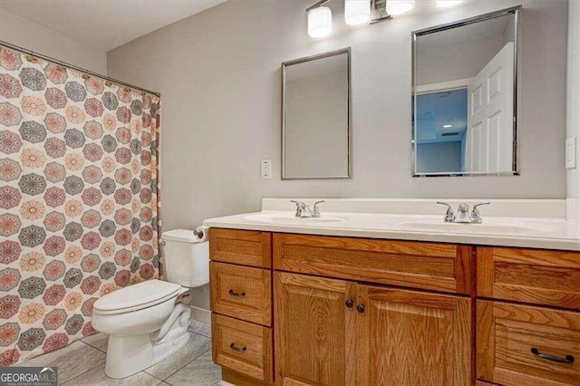 bathroom featuring toilet, tile patterned flooring, double vanity, and a sink