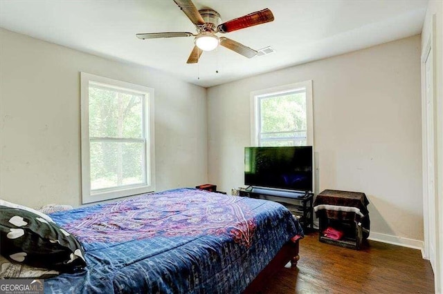 bedroom with dark wood-type flooring, multiple windows, and ceiling fan