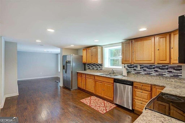 kitchen featuring light stone countertops, decorative backsplash, stainless steel appliances, dark wood-type flooring, and sink