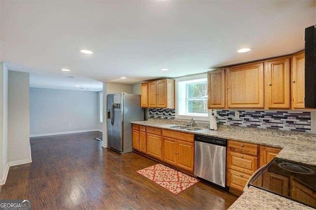 kitchen featuring stainless steel appliances, backsplash, a sink, baseboards, and dark wood-style floors
