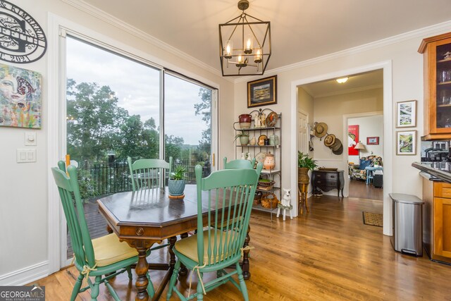 dining room featuring wood-type flooring, ornamental molding, and a notable chandelier