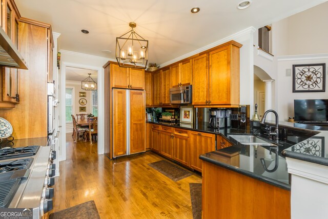 kitchen featuring appliances with stainless steel finishes, dark hardwood / wood-style flooring, ornamental molding, and wall chimney exhaust hood