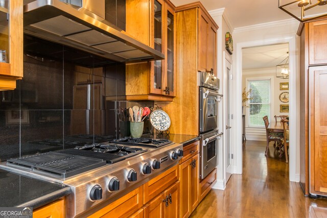 kitchen featuring decorative backsplash, appliances with stainless steel finishes, crown molding, wood-type flooring, and range hood