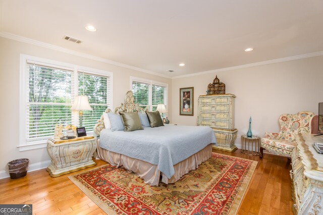 bedroom with wood-type flooring, ornamental molding, and multiple windows