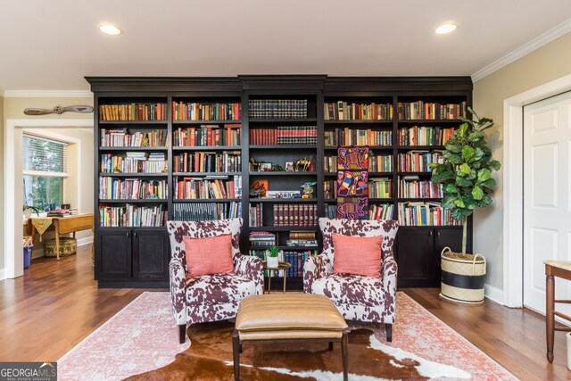 living area with hardwood / wood-style flooring and ornamental molding