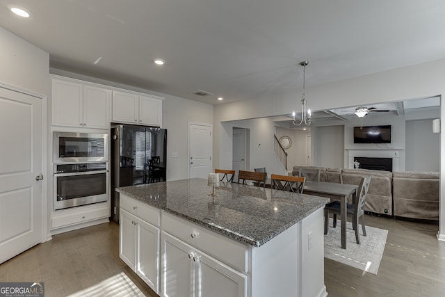 kitchen featuring a center island, dark stone counters, white cabinetry, light hardwood / wood-style flooring, and appliances with stainless steel finishes