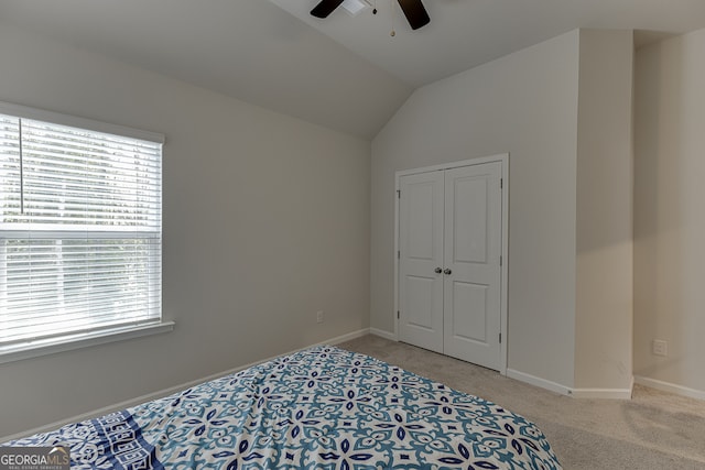 bedroom featuring ceiling fan, a closet, light carpet, and vaulted ceiling