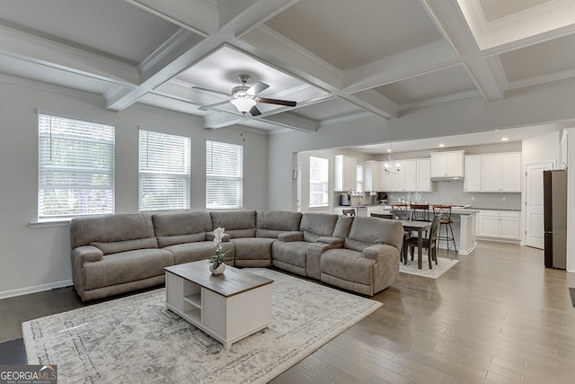 living room featuring ceiling fan, light hardwood / wood-style floors, crown molding, coffered ceiling, and beam ceiling