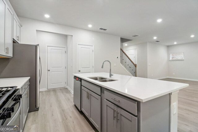 kitchen featuring light hardwood / wood-style flooring, an island with sink, gray cabinetry, stainless steel appliances, and sink