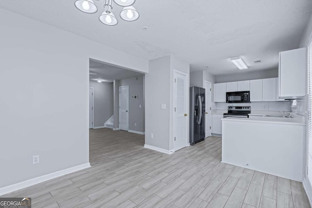 kitchen with sink, white cabinetry, appliances with stainless steel finishes, an inviting chandelier, and light hardwood / wood-style floors