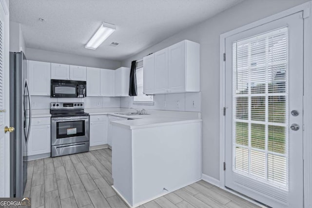 kitchen featuring stainless steel appliances, light hardwood / wood-style floors, white cabinets, and a textured ceiling