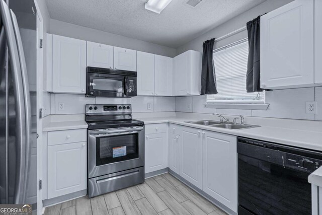 kitchen featuring sink, a textured ceiling, white cabinetry, black appliances, and light wood-type flooring