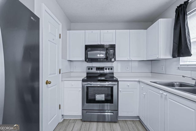 kitchen featuring black appliances, sink, a textured ceiling, and white cabinetry