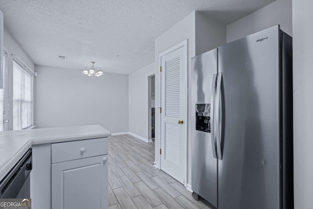 kitchen featuring a chandelier, light wood-type flooring, pendant lighting, white cabinets, and appliances with stainless steel finishes