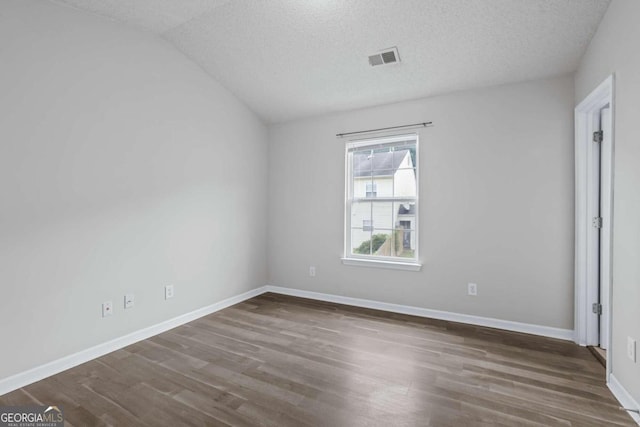 unfurnished bedroom featuring lofted ceiling, dark hardwood / wood-style floors, and a textured ceiling