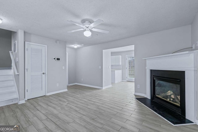 unfurnished living room with a textured ceiling, ceiling fan, and light hardwood / wood-style flooring