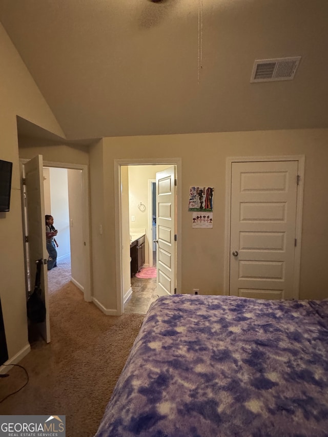 carpeted bedroom with lofted ceiling and ensuite bath