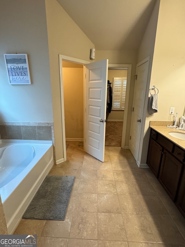 bathroom with vanity, a tub, and lofted ceiling