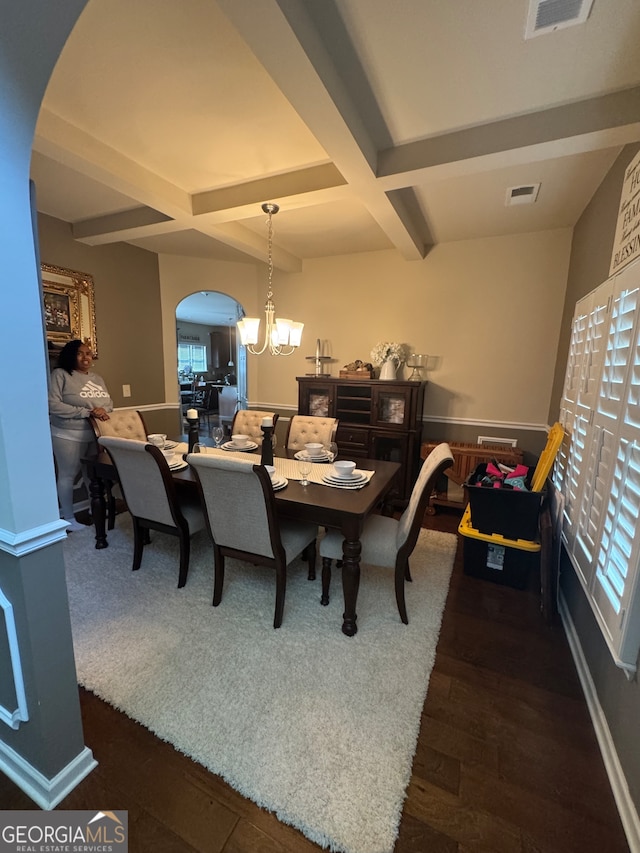 dining room with dark wood-type flooring, beam ceiling, and an inviting chandelier