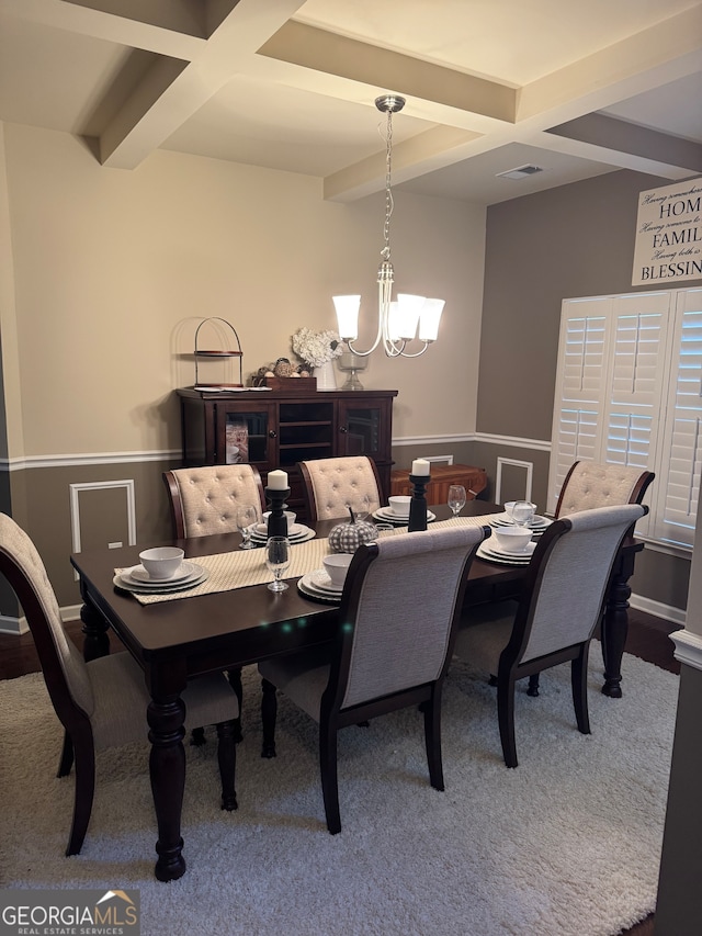 dining room with beam ceiling, coffered ceiling, carpet flooring, and a chandelier