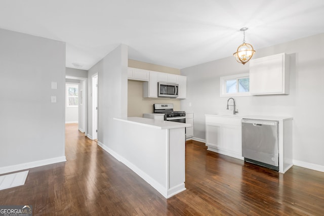 kitchen with appliances with stainless steel finishes, pendant lighting, a wealth of natural light, and white cabinets