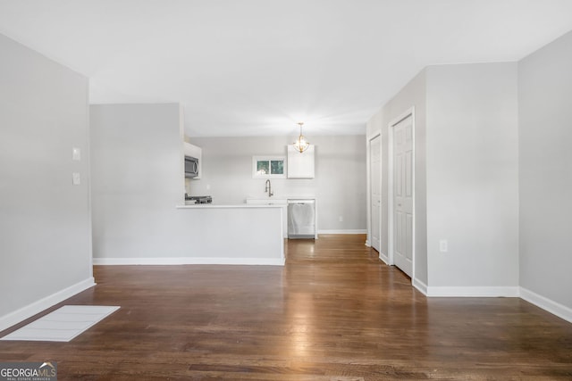 unfurnished living room with a notable chandelier, dark hardwood / wood-style flooring, and sink