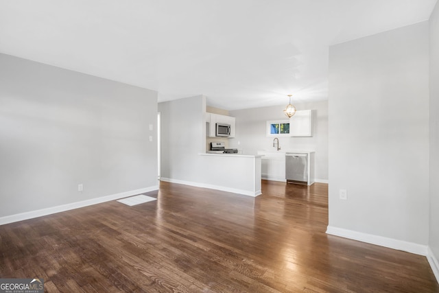 unfurnished living room featuring sink, a chandelier, and dark hardwood / wood-style floors