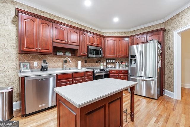 kitchen with sink, a kitchen island, light hardwood / wood-style flooring, stainless steel appliances, and crown molding