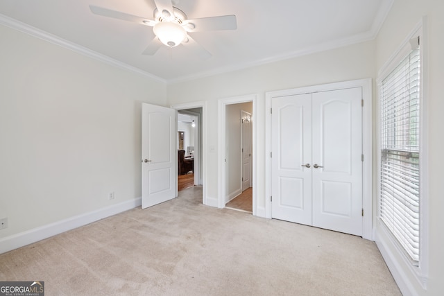 unfurnished bedroom featuring light carpet, crown molding, ceiling fan, and a closet