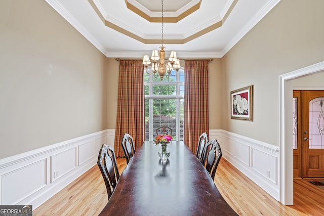 dining space with an inviting chandelier, light hardwood / wood-style flooring, crown molding, and a tray ceiling