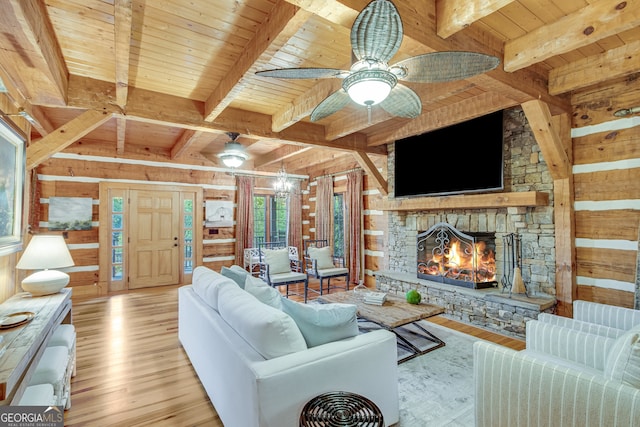 living room featuring light wood-type flooring, wooden walls, beamed ceiling, a stone fireplace, and wooden ceiling