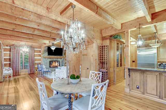 dining area featuring a stone fireplace, beamed ceiling, wood ceiling, and light hardwood / wood-style floors