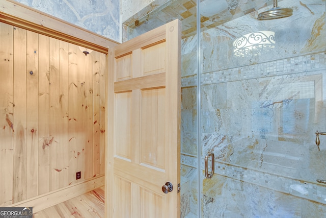 room details featuring a shower with shower door and wood walls