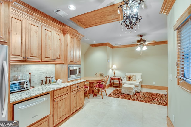 kitchen with light brown cabinetry, hanging light fixtures, sink, and tasteful backsplash