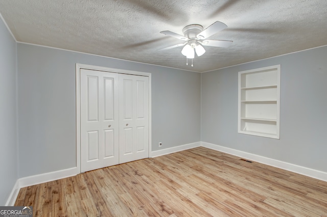 unfurnished bedroom featuring a textured ceiling, a closet, light wood-type flooring, and ceiling fan