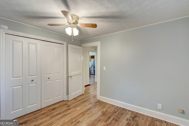 unfurnished bedroom featuring a closet, light hardwood / wood-style flooring, a textured ceiling, and ceiling fan