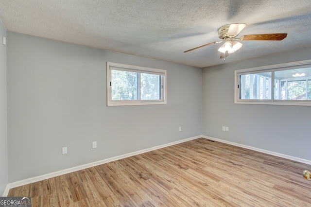 unfurnished room featuring a textured ceiling, light wood-type flooring, and a healthy amount of sunlight