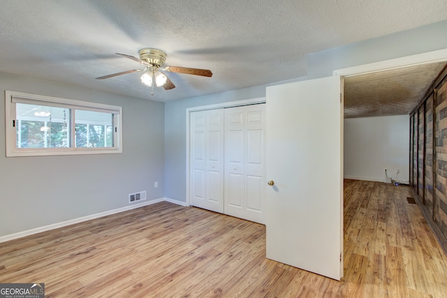 unfurnished bedroom featuring ceiling fan, a textured ceiling, light hardwood / wood-style flooring, and a closet