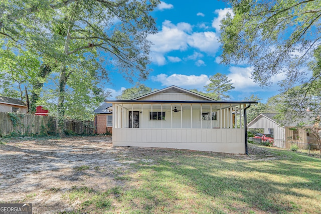 back of property with ceiling fan and a lawn