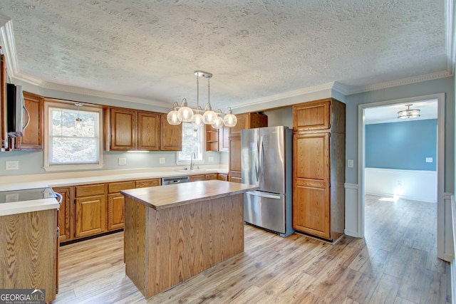 kitchen with pendant lighting, sink, a kitchen island, light hardwood / wood-style flooring, and stainless steel appliances