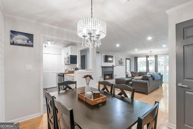 dining area with ornamental molding, a textured ceiling, and light wood-type flooring