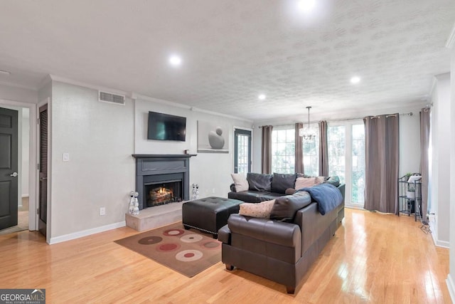 living room with crown molding, a textured ceiling, and light wood-type flooring