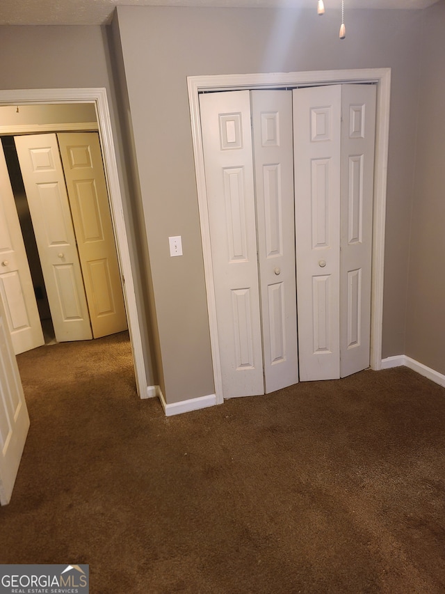 unfurnished bedroom with a closet and dark colored carpet