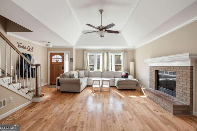 living room featuring ceiling fan, crown molding, light hardwood / wood-style flooring, a fireplace, and lofted ceiling