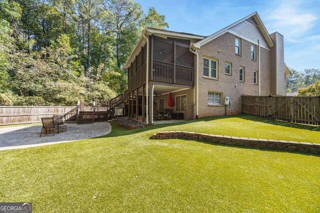 back of house featuring a sunroom, a lawn, and a patio area