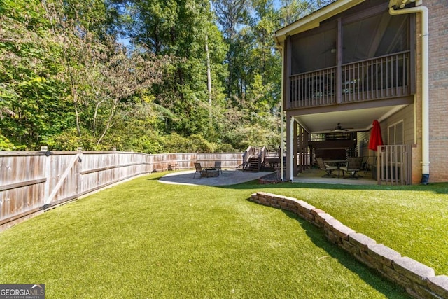 view of yard with ceiling fan, a fire pit, a sunroom, and a patio area